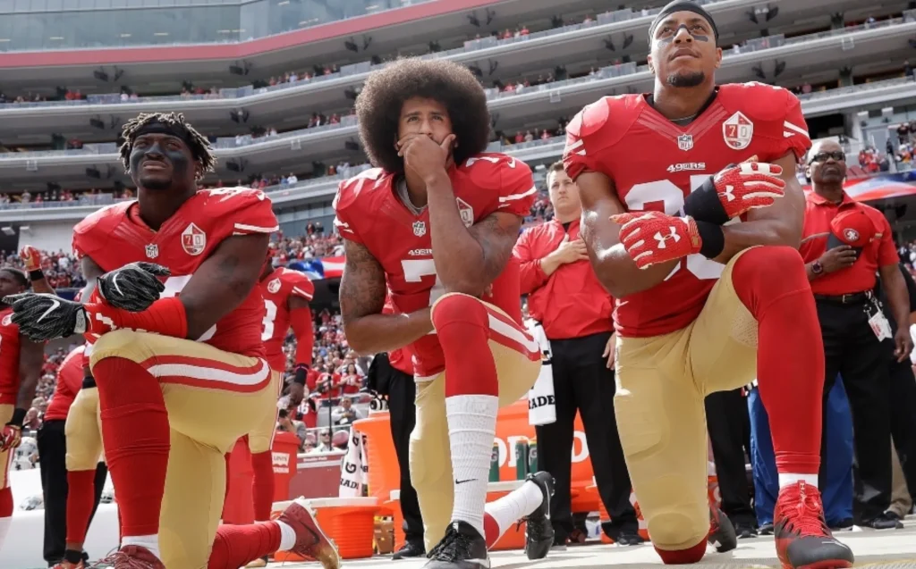Jugadores de fútbol americano arrodillados durante el himno